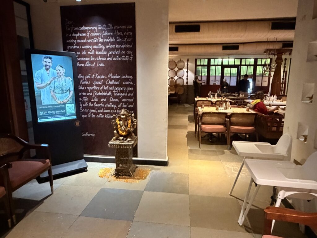 Digital advertising display beside waiting chairs and a decorative statue at the entrance to Itlu Jubilee Hills.