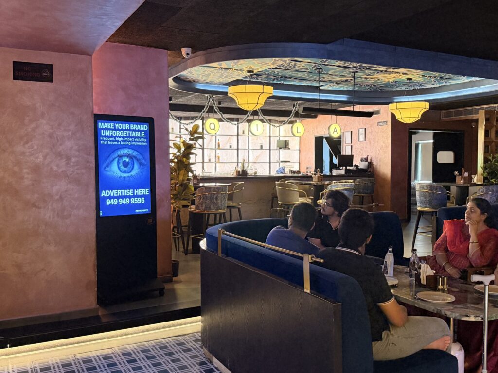Aira Konnect advertising screen beside occupied lounge seating and the bar at Taqila Bachupally.